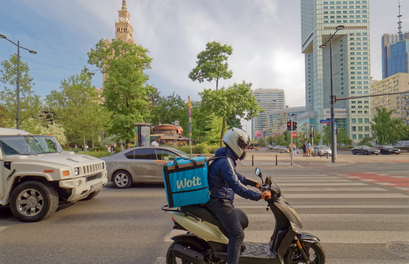 Wolt food delivery courier navigating city traffic on a scooter